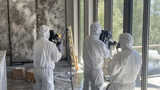Remediation team in protective suits working inside a contained mold affected room