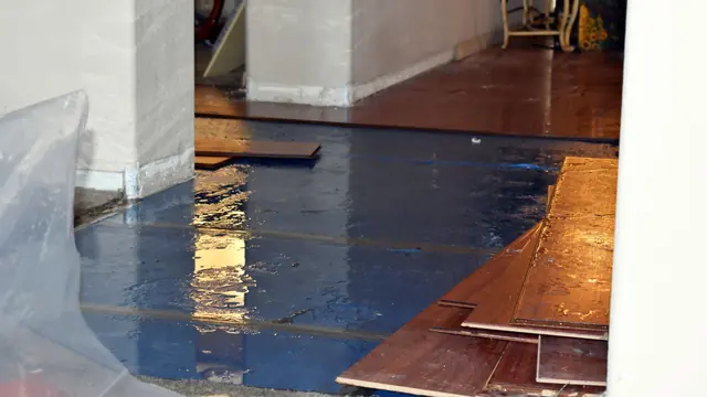Hardwood floorboards lifted from the subfloor with protective sheeting beside them