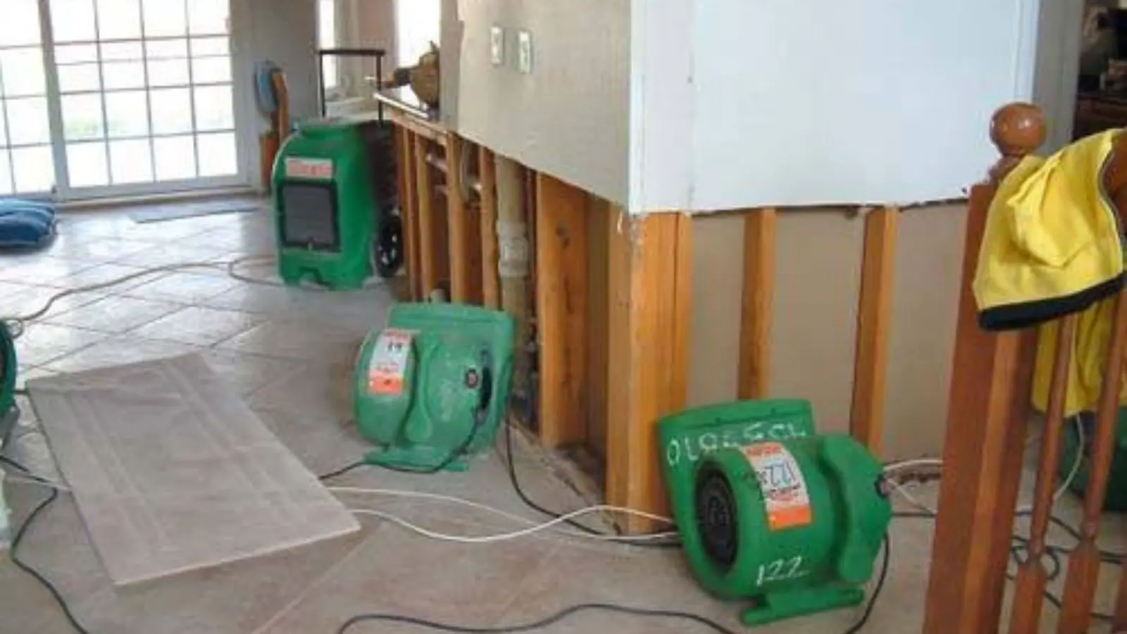 Air movers drying a room where the lower wall sections have been opened after water damage